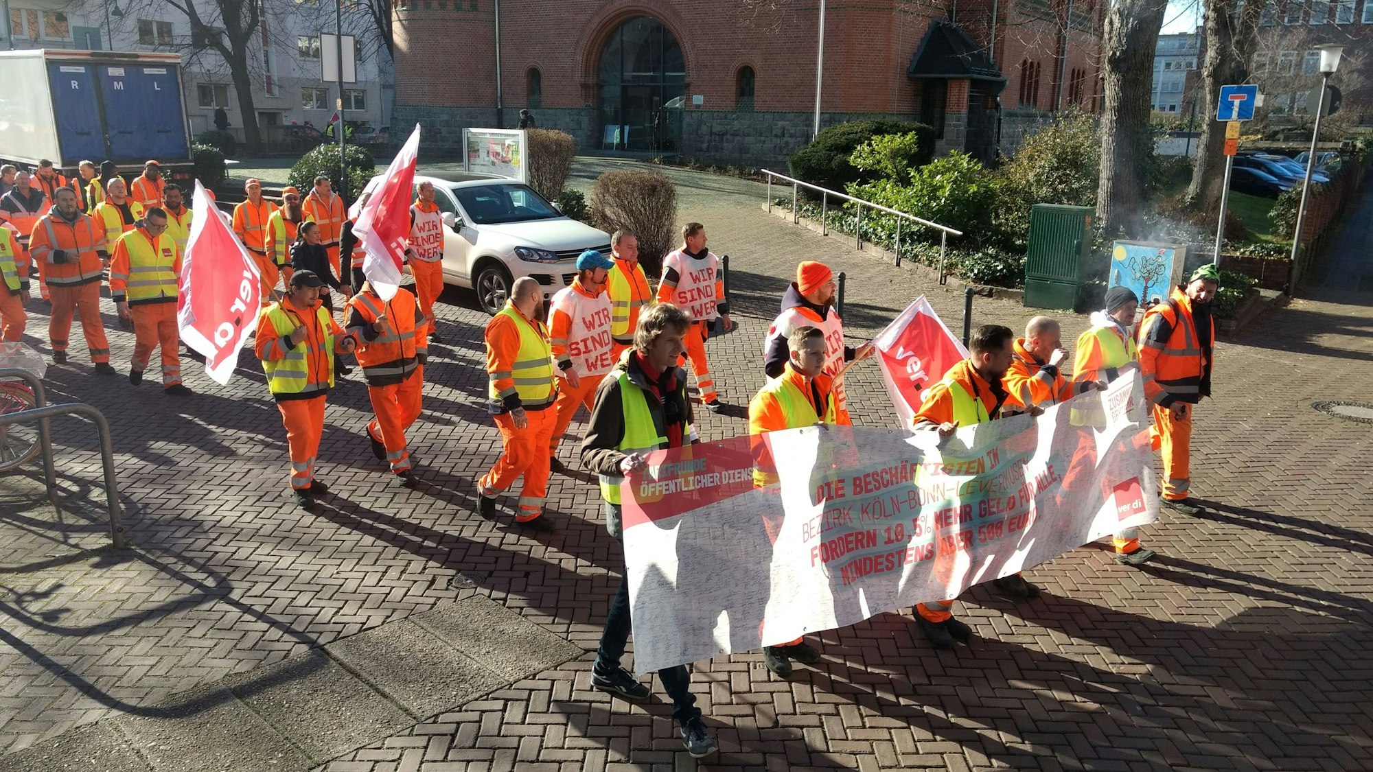 Teilnehmende des Verdi-Warnstreiks laufen mit Warnwesten durch Leverkusen-Wiesdorf.