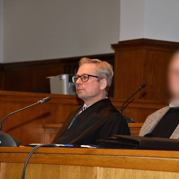Ein Pfarrer (Gesicht gepixelt) sitzt neben seinem Anwalt im Gerichtssaal.