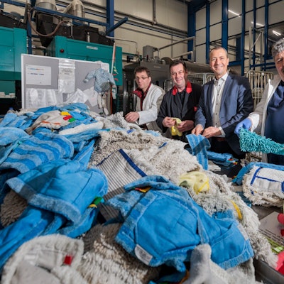 Mehrere Männer stehen hinter einem Berg von bunten Wischbezügen.