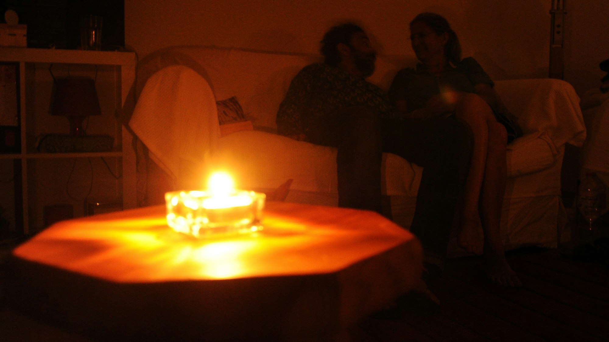 Ein Paar sitzt während eines Stromausfalls bei Kerzenschein in einer Wohnung.