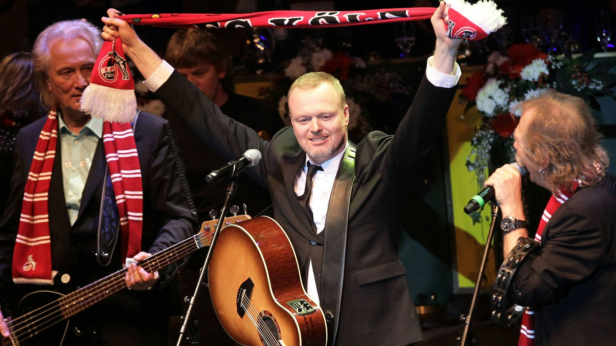 Stefan Raab singt mit der Band Höhner und hält einen FC-Schal hoch.