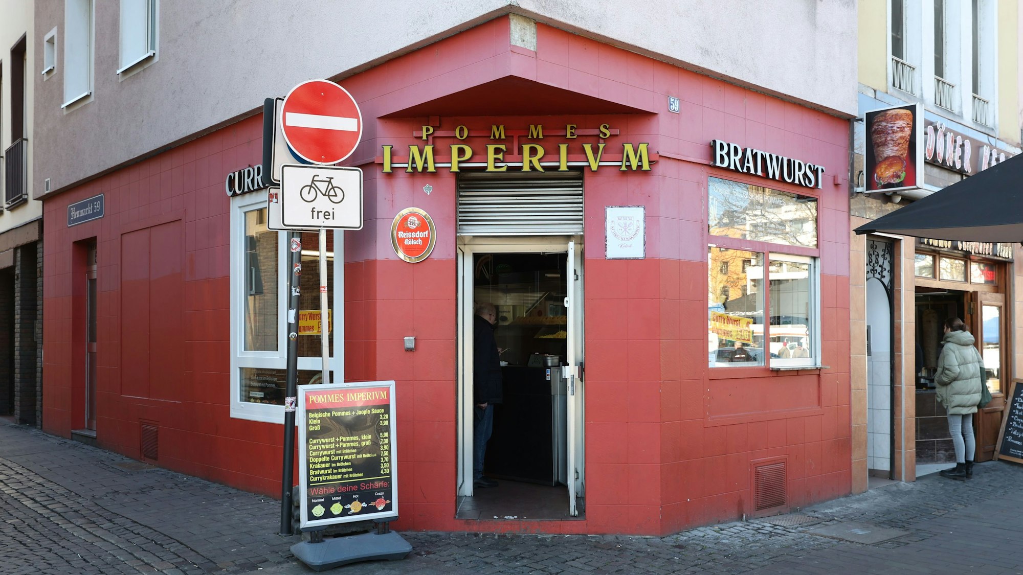 Außenansicht des Pommes Imperium mit seiner roten Fassade, die Tür ist geöffnet.