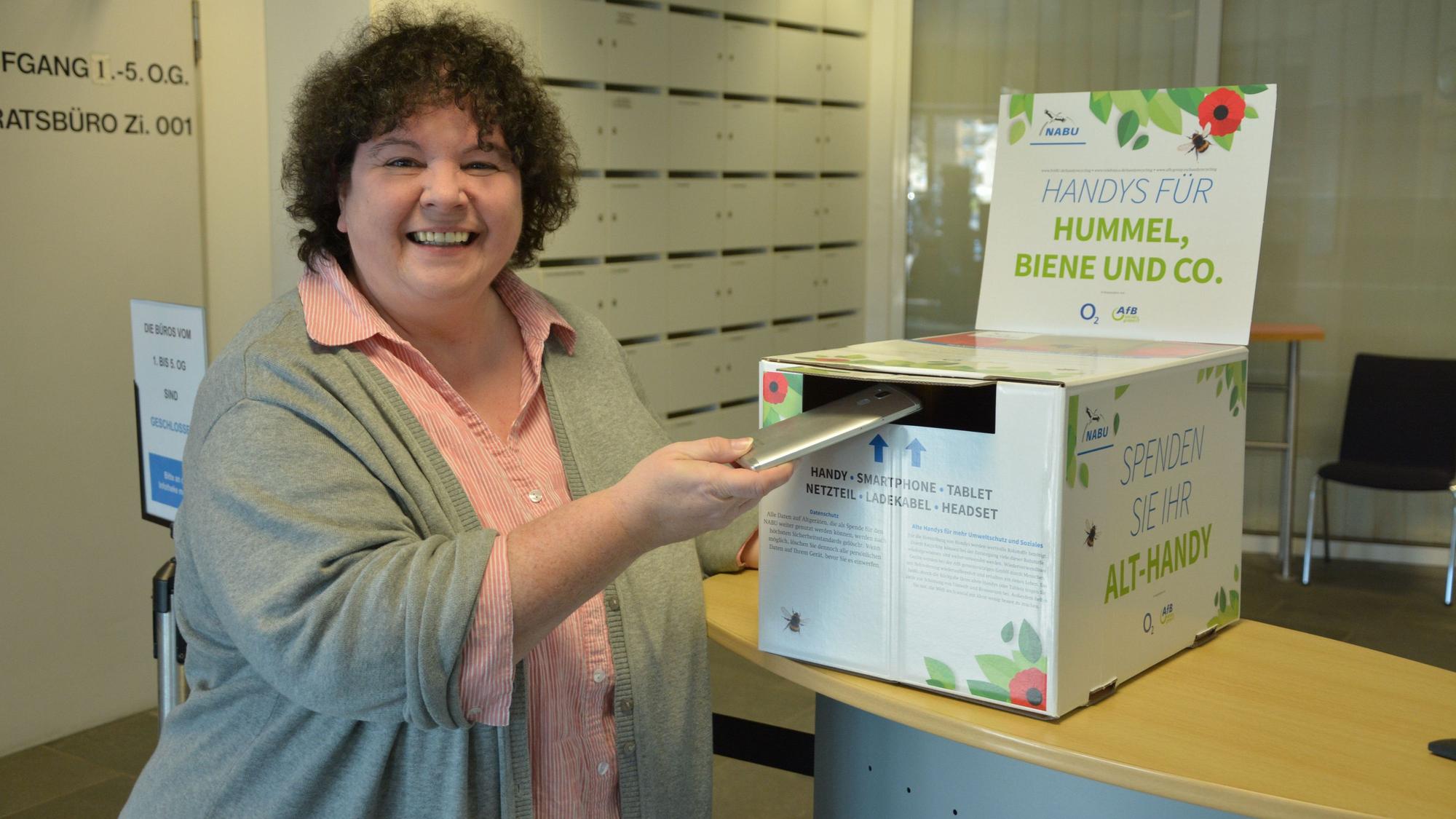 Klimaschutzmanagerin Monika Meves wirft ein Handy in die Sammelbox des Nabu im Leichlinger Rathausfoyer ein.