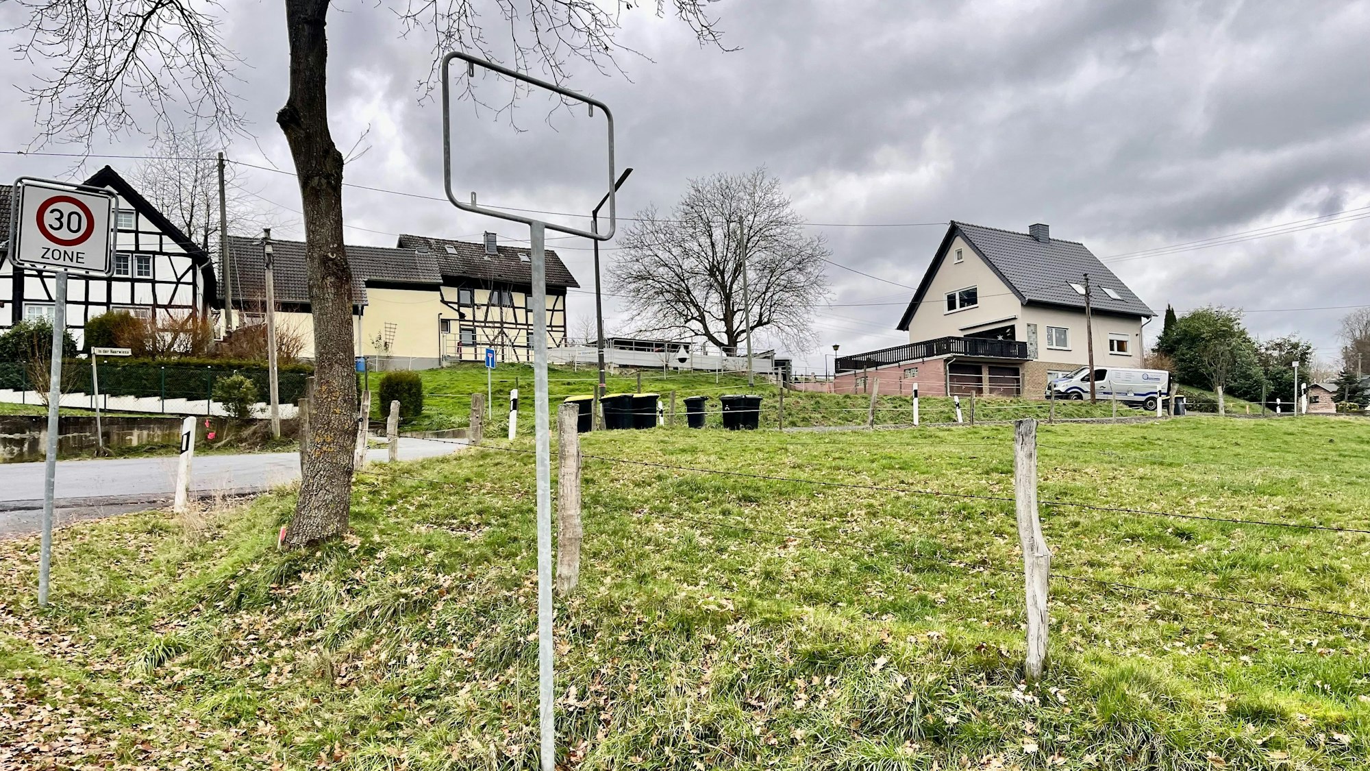 Im Vordergrund die leere Halterung des Schildes, im Hintergrund der Ort selbst.