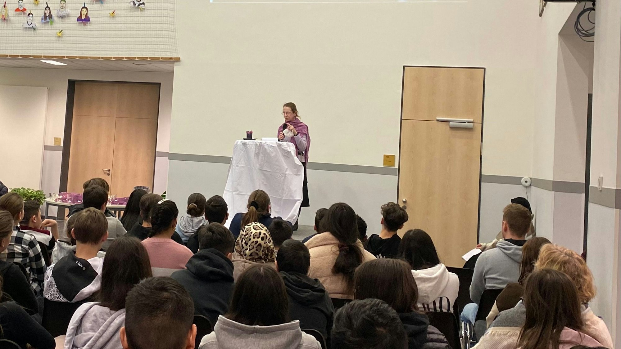 Zu sehen ist eine Gedenkfeier mit einer Frau am Rednerpult.