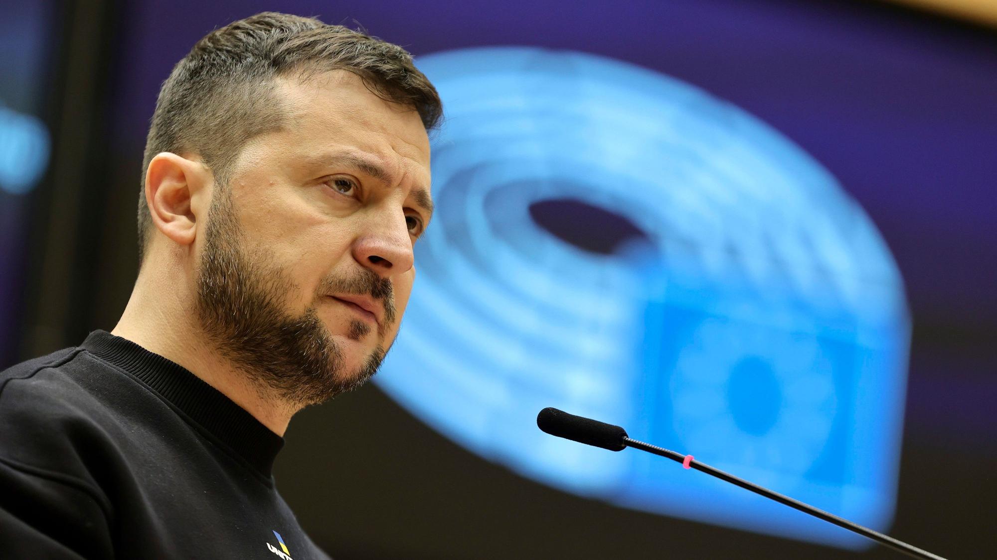 Wolodymyr Selenskyj, Präsident der Ukraine, spricht bei einem EU-Gipfel im Europäischen Rat in Brüssel. Selenskyjs ist im Profil zu sehen, vor ihm ein Mikrofon, hinter ihm eine blau ausgeleuchtete Wand.