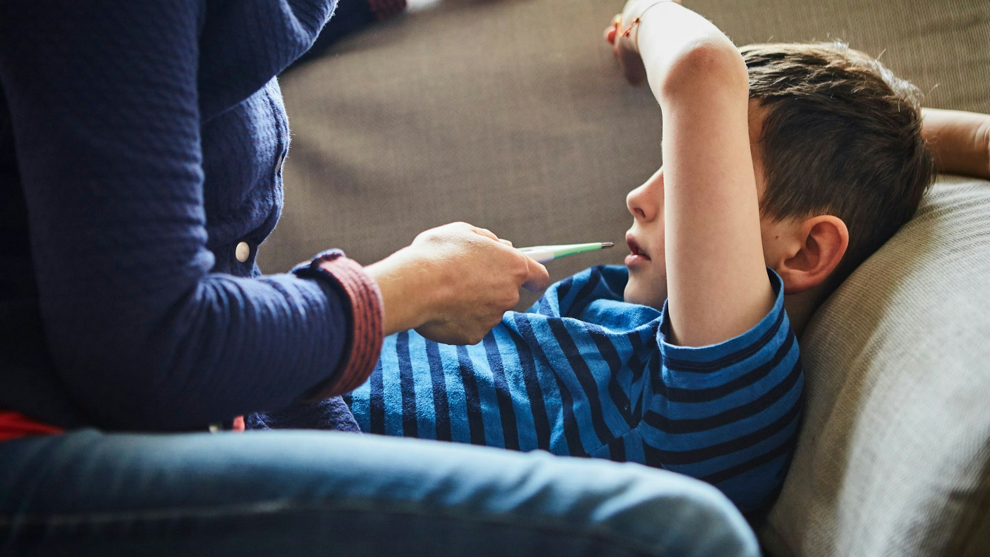 Eine Mutter misst Fieber bei ihrem kranken Sohn.
