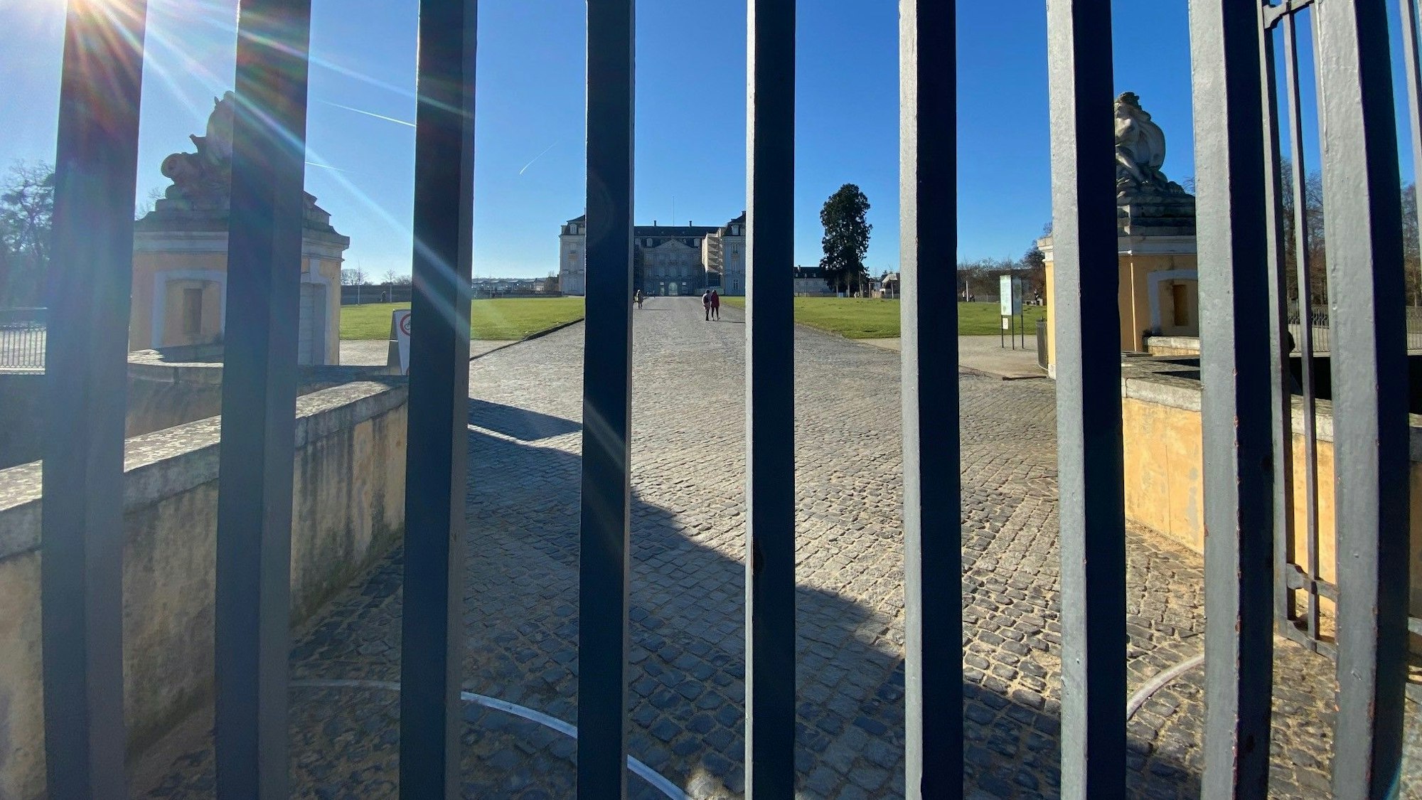 Auf dem Foto ist durch die Streben des verschlossenen Parks der Schlosspark zu sehen.