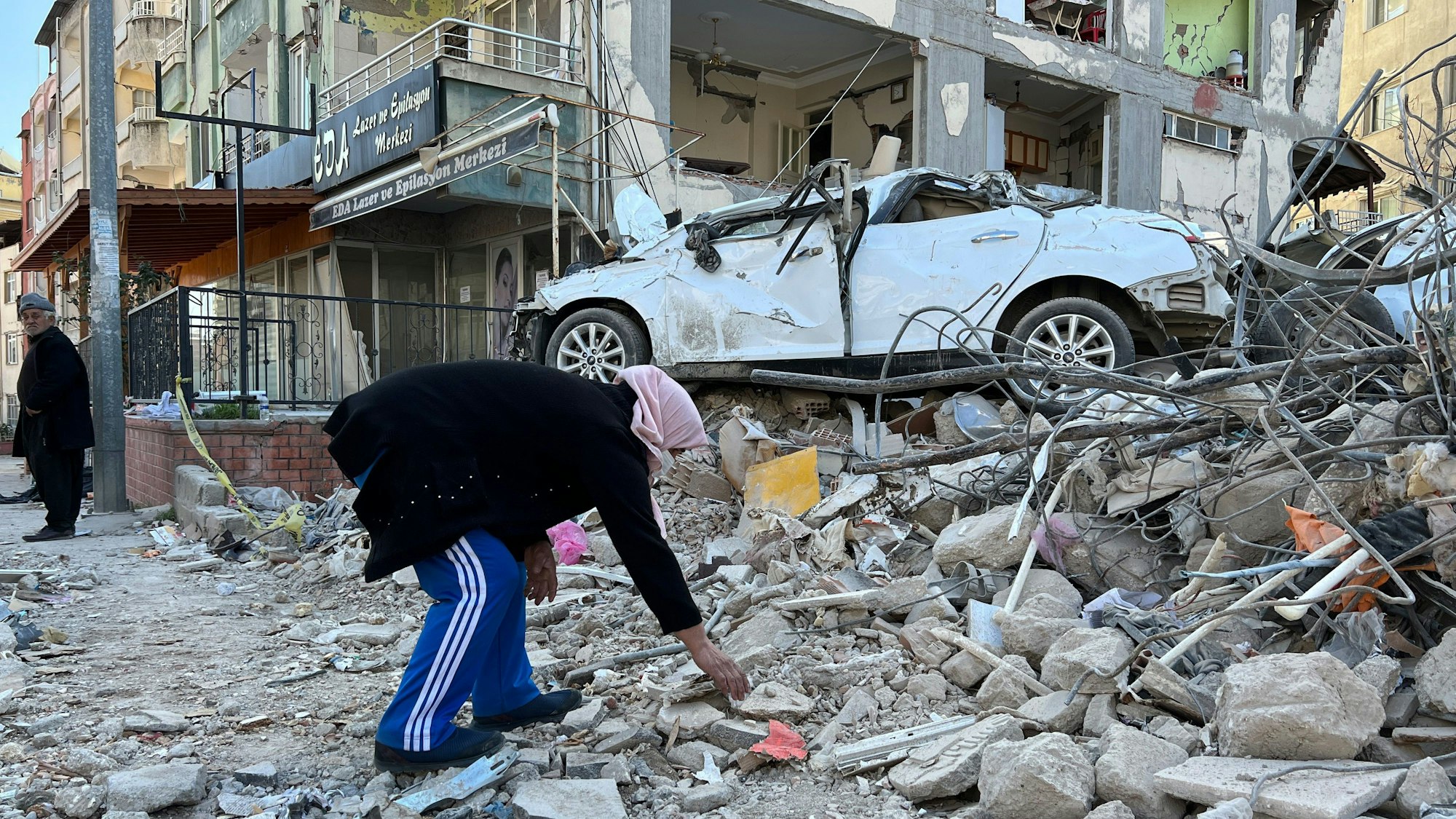 Eine Frau sucht nach Brennmaterial zwischen den Trümmern von Gebäuden.