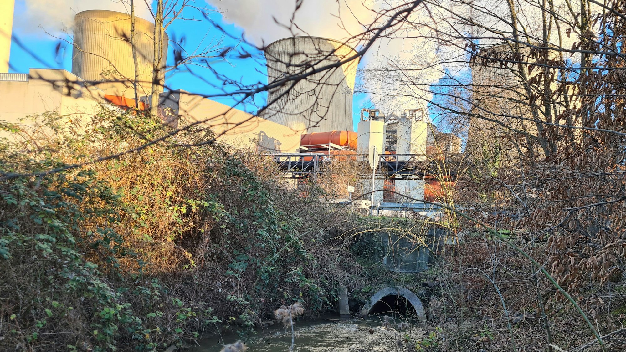 Der Gillbach tritt aus einem Kanal aus, im Hintergrund das Kraftwerk.