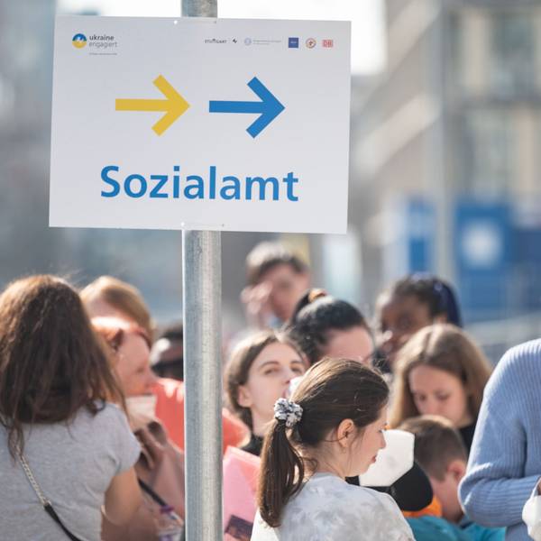 Das Schild Sozialamt steht inmitten einer Menschenmenge.