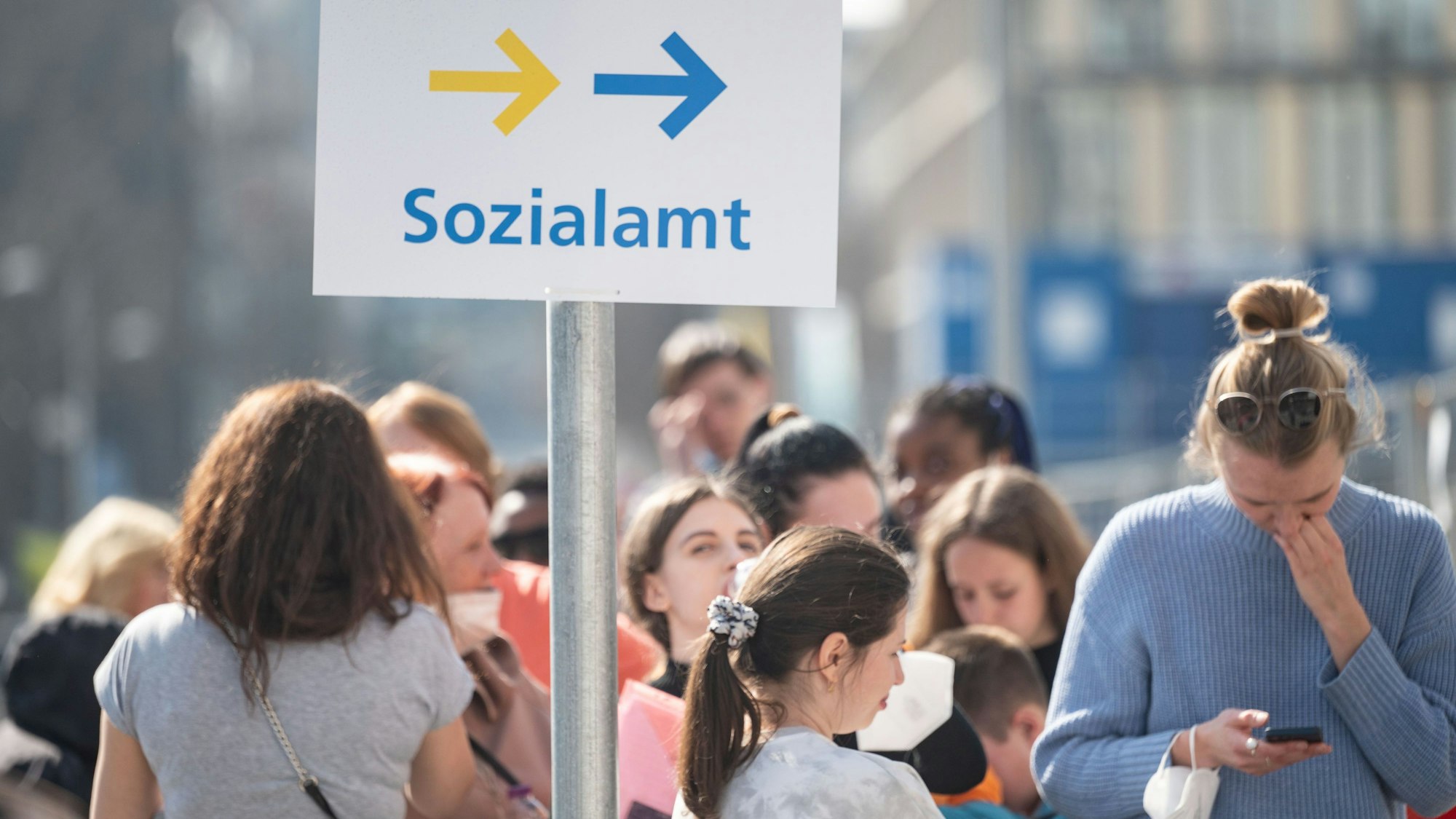Das Schild Sozialamt steht inmitten einer Menschenmenge.