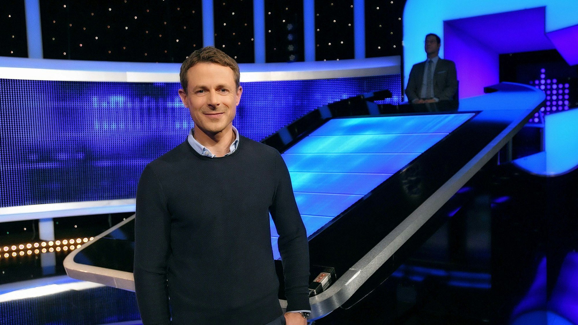 Moderator Alexander Bommes steht in der Studiokulisse von „Gefragt - Gejagt“.