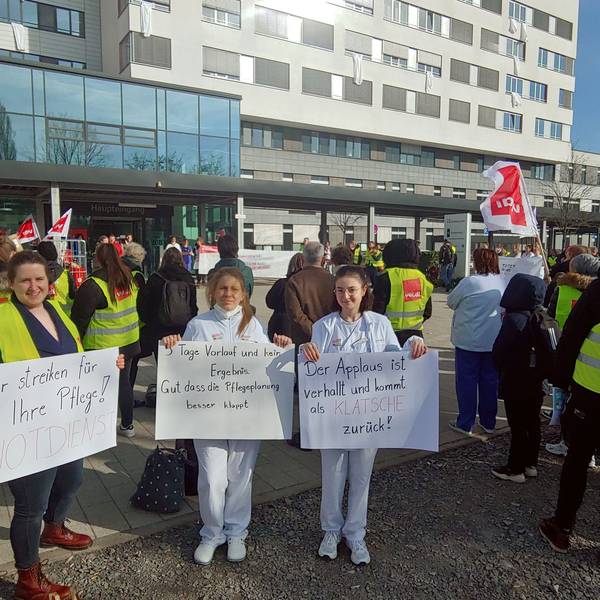 Klinikmitarbeiterinnen mit Schildern vor dem Klinikgelände