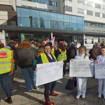 Klinikmitarbeiterinnen mit Schildern vor dem Klinikgelände