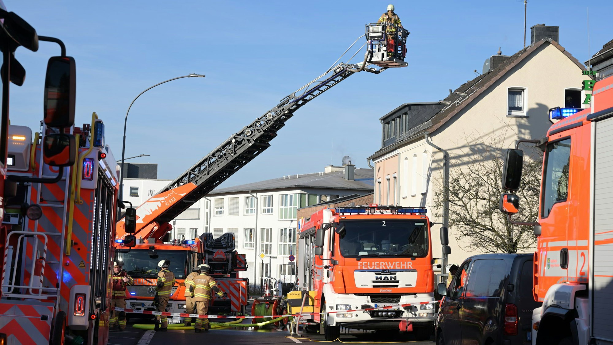 Feuerwehrautos und eine Drehleiter stehen auf einer für den Verkehr gesperrten Straße.