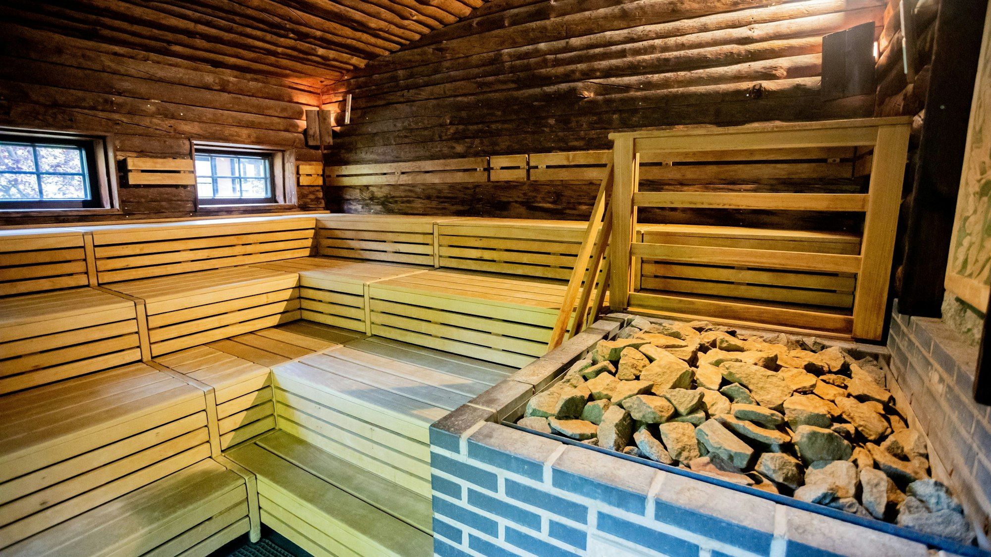 Eine Holzsauna mit mehreren Stufen, Steine liegen auf dem Ofen.