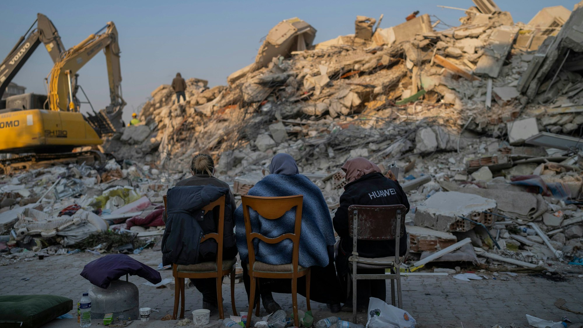 Frauen sitzen in Antakya vor Schuttbergen nach dem Erdbeben.