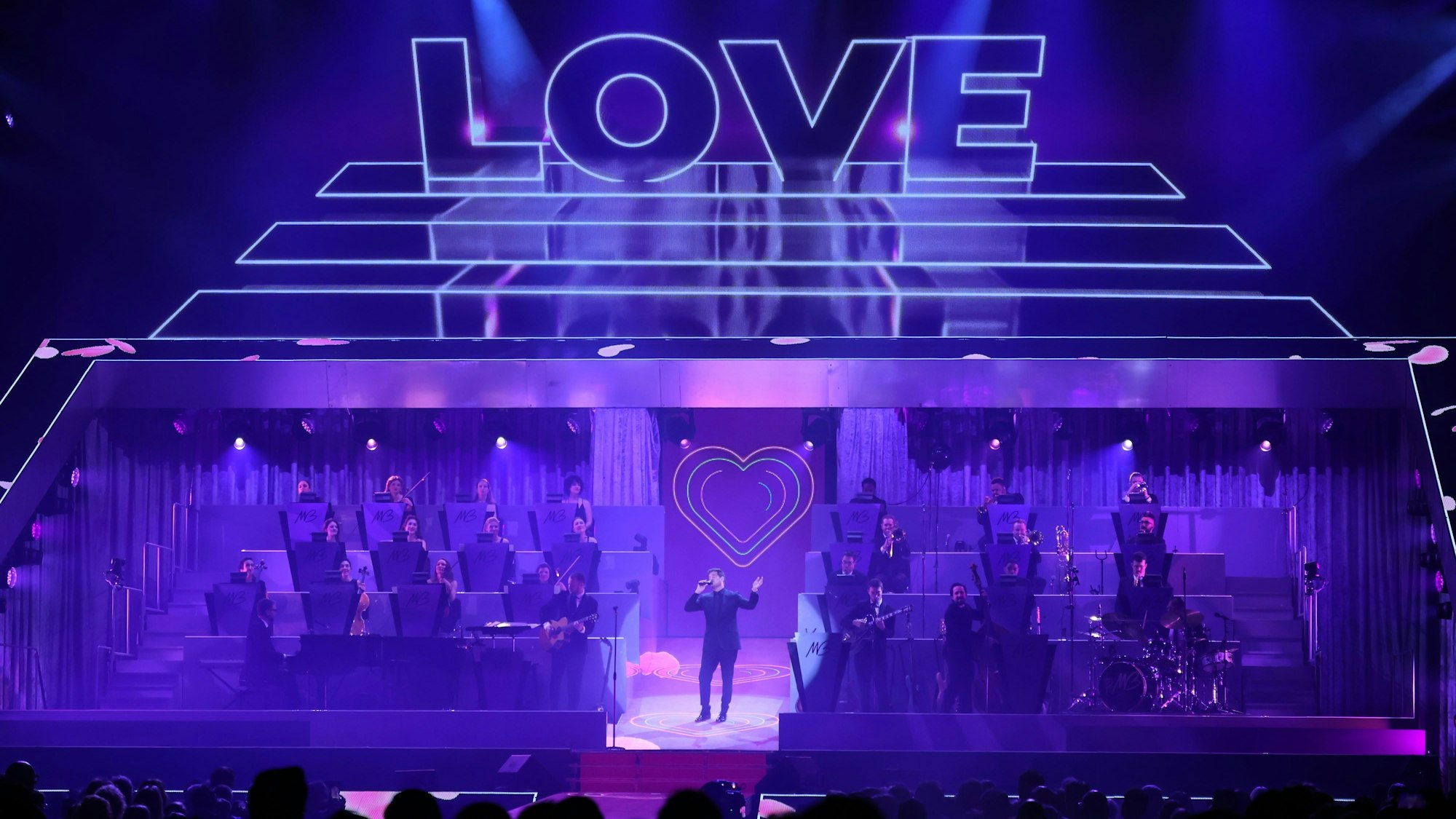 Michael Bublé und die Big Band in einem Weitwinkel. Über ihnen steht das Wort Love.