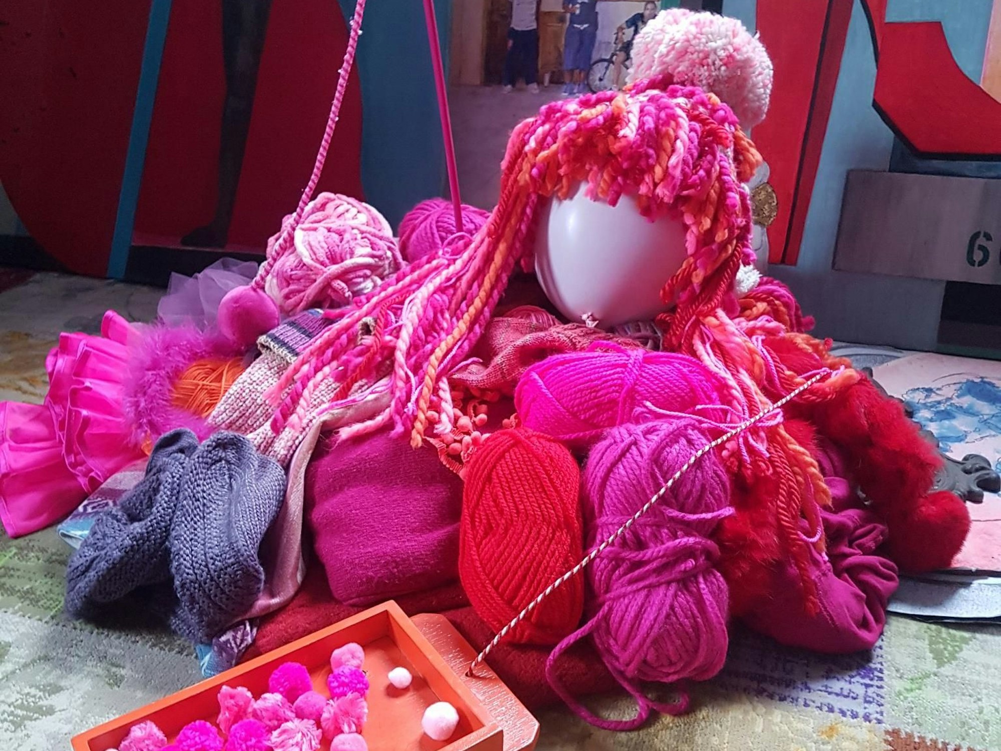 Auf einem kleinen Holzwagen ist ein Wollknäulkätzchen platziert.