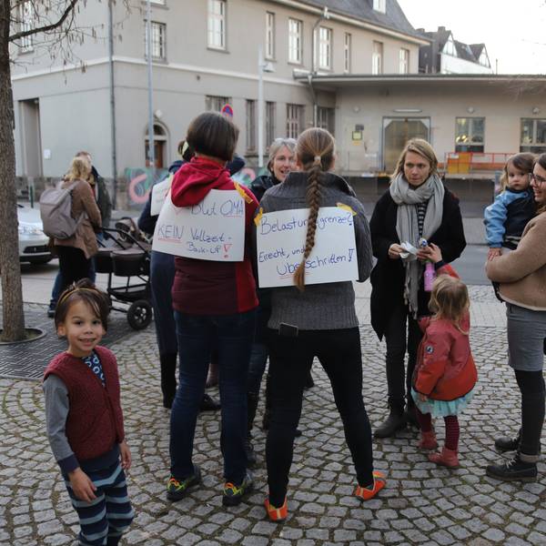 Eltern und Kinder haben sich auf einem Platz versammelt.