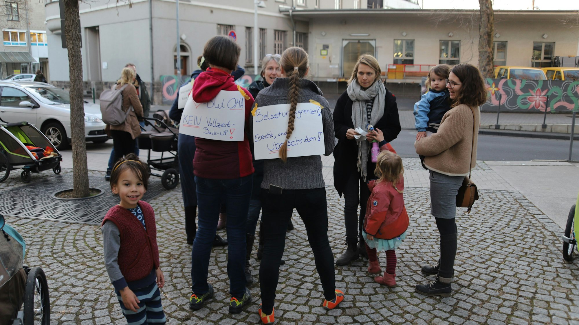 Eltern und Kinder haben sich auf einem Platz versammelt.
