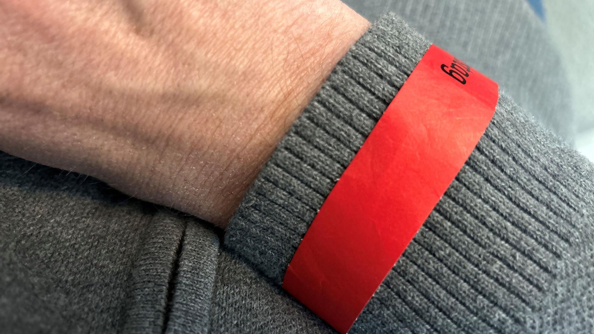 Offizielles, rotes Zutrittsbändchen für Weiberfastnacht an einem Arm
