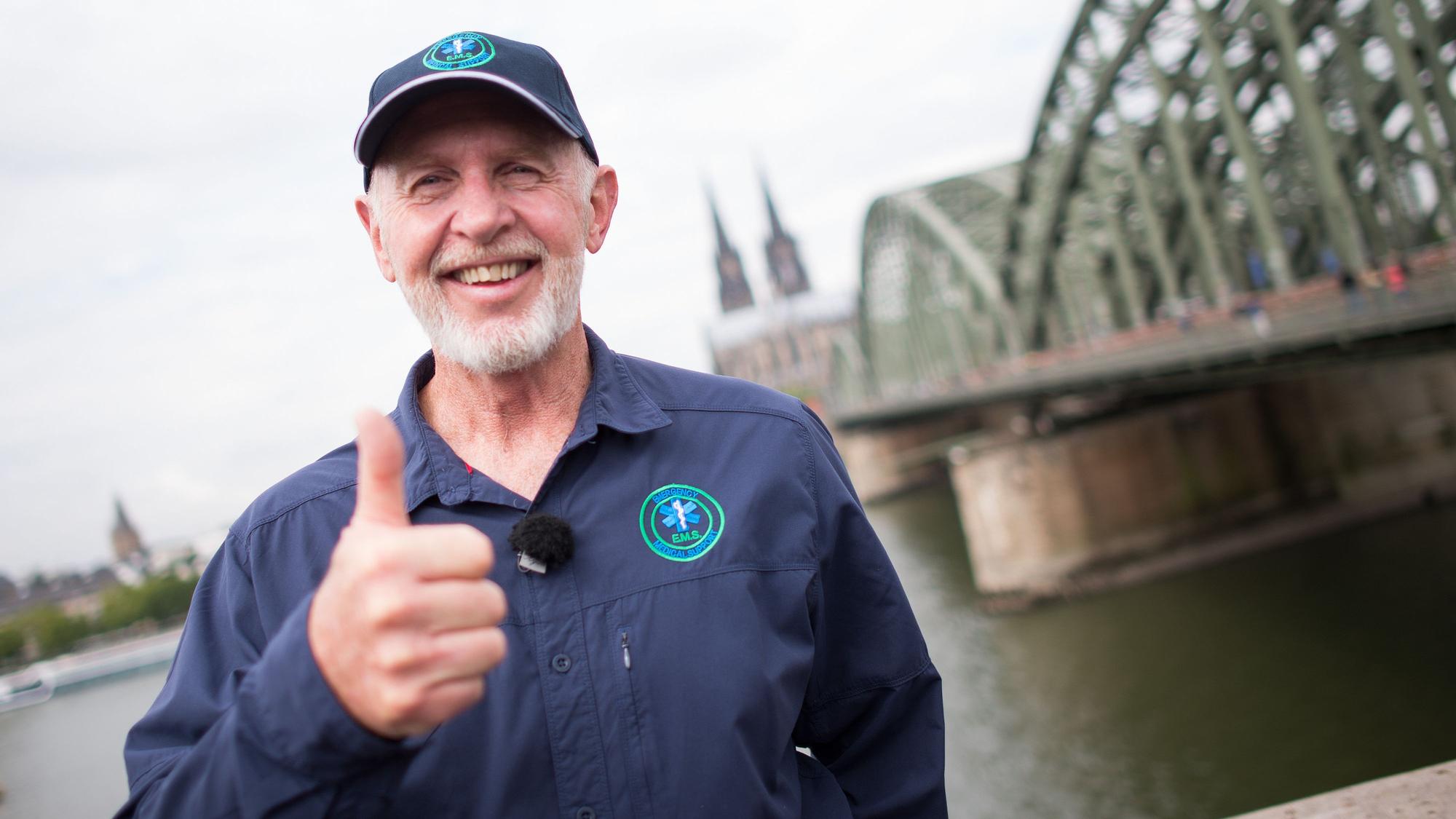 Dr. Bob posiert am Rheinufer in Köln vor dem Dom und der Hohenzollernbrücke.
