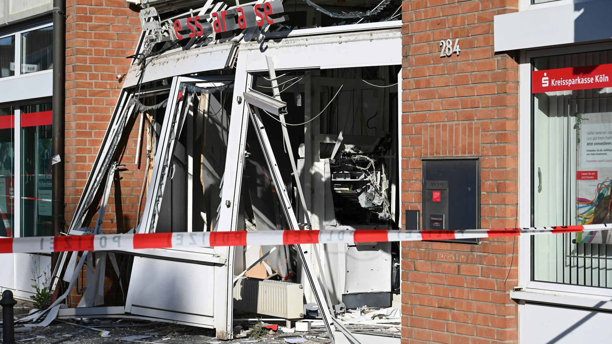 Ein zerstörter, explodierter Geldautomat an der Dürener Straße hinter rot-weißem Absperrband.