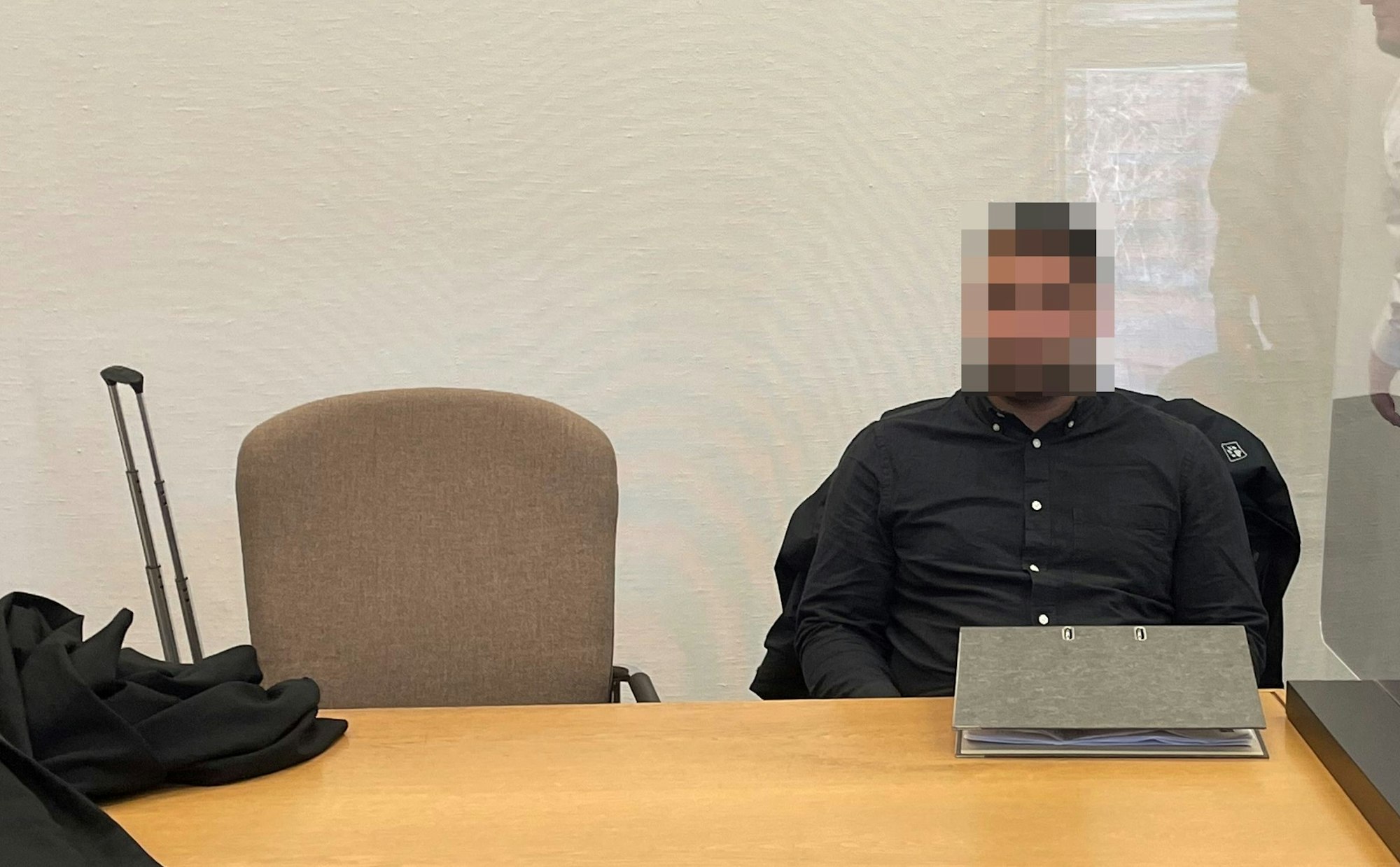 Der Angeklagte sitzt im schwarzen Hemd auf der Anklagebank.