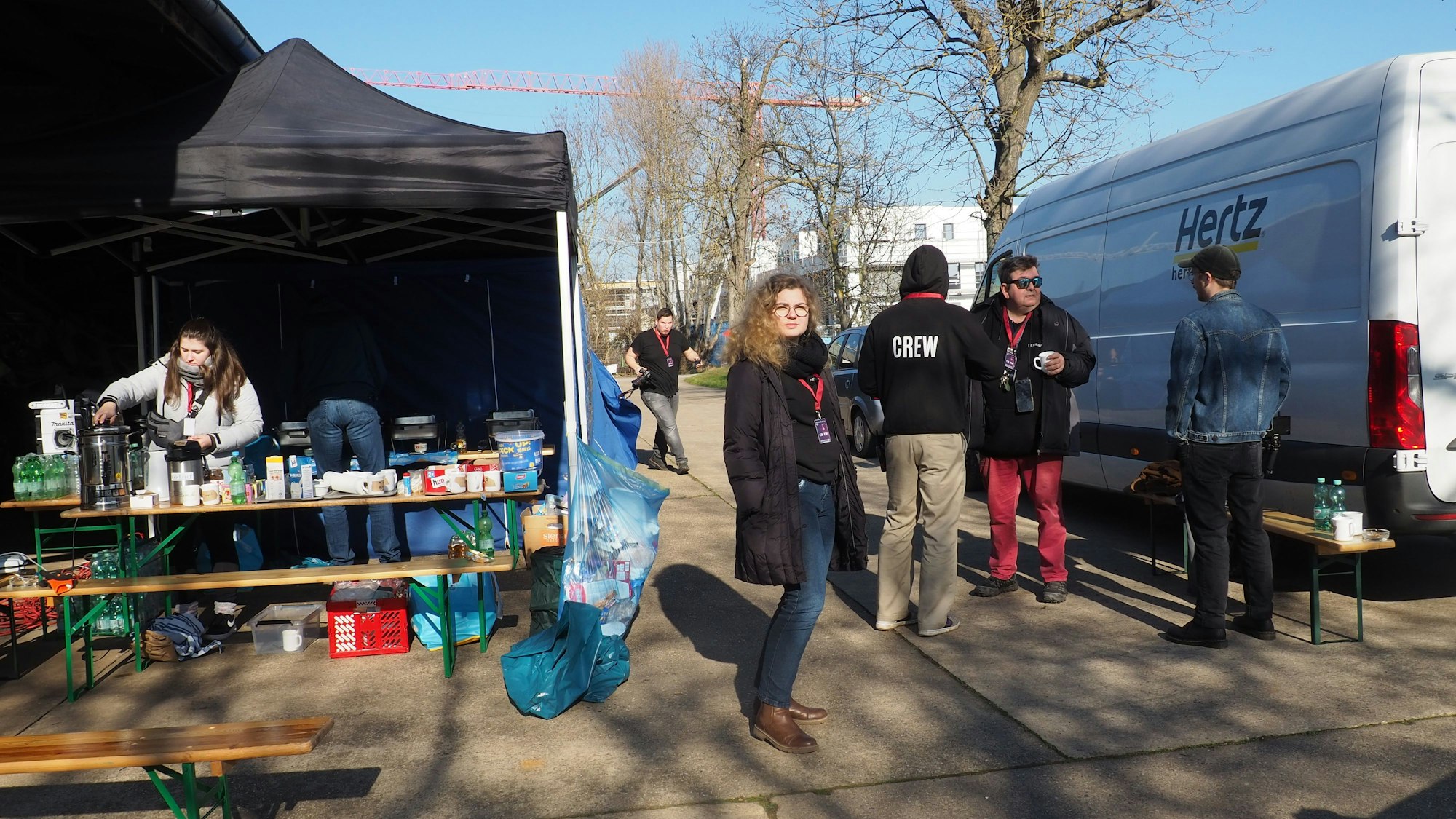 Mitglieder der Crew stehen auf dem Parkplatz und bereiten das Catering vor.