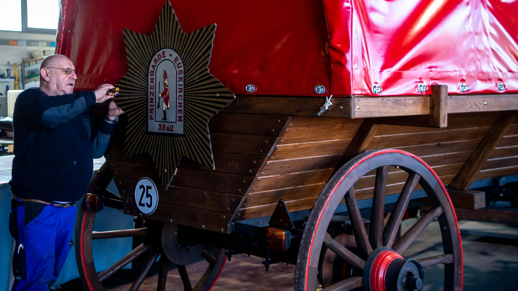 Das Bild zeigt den historischen Planwagen der Prinzengarde. Ein Mann montiert gerade ein Schild.
