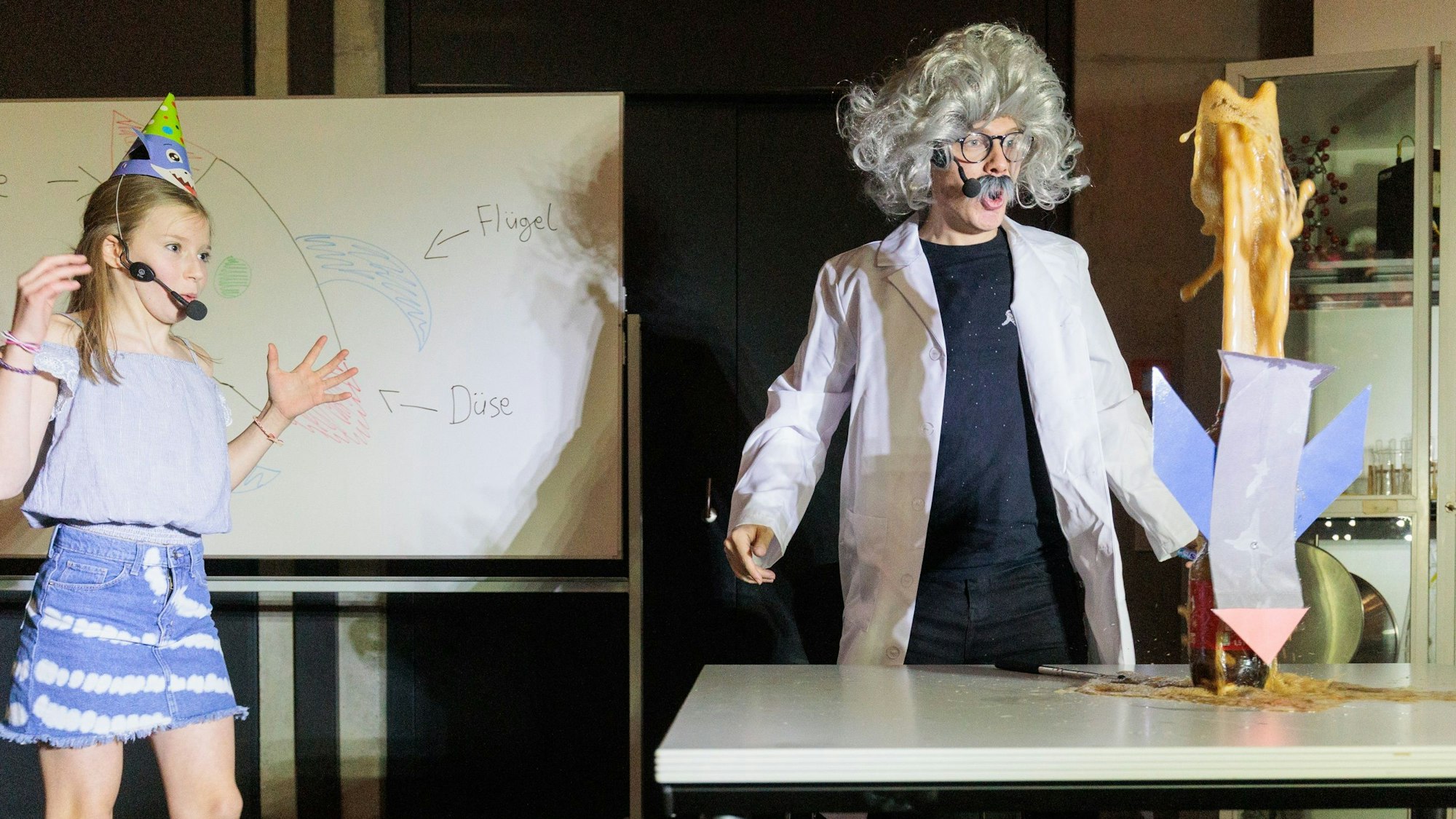Im Theaterstück lässt der zerstreute Professor eine Cola-Flasche übersprudeln.