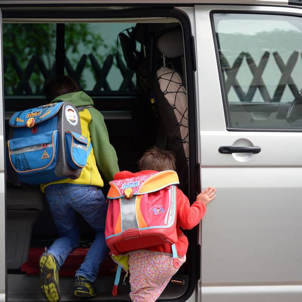 Schulkinder steigen in ein privates Fahrzeug.