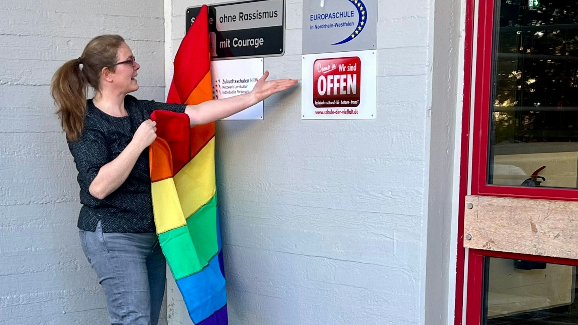 Alexa Mönning nimmt eine Regenbogenflagge von der Plakette.