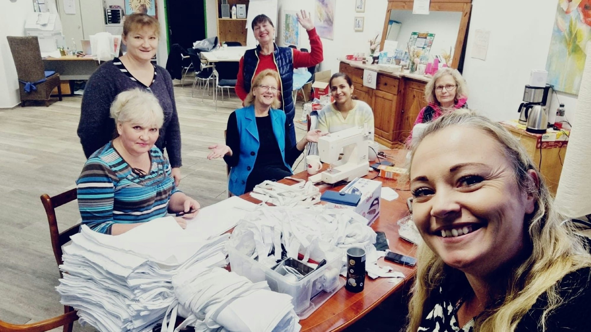 Mehrere Frauen sitzen an einem Tisch und nähen die Kostüme.