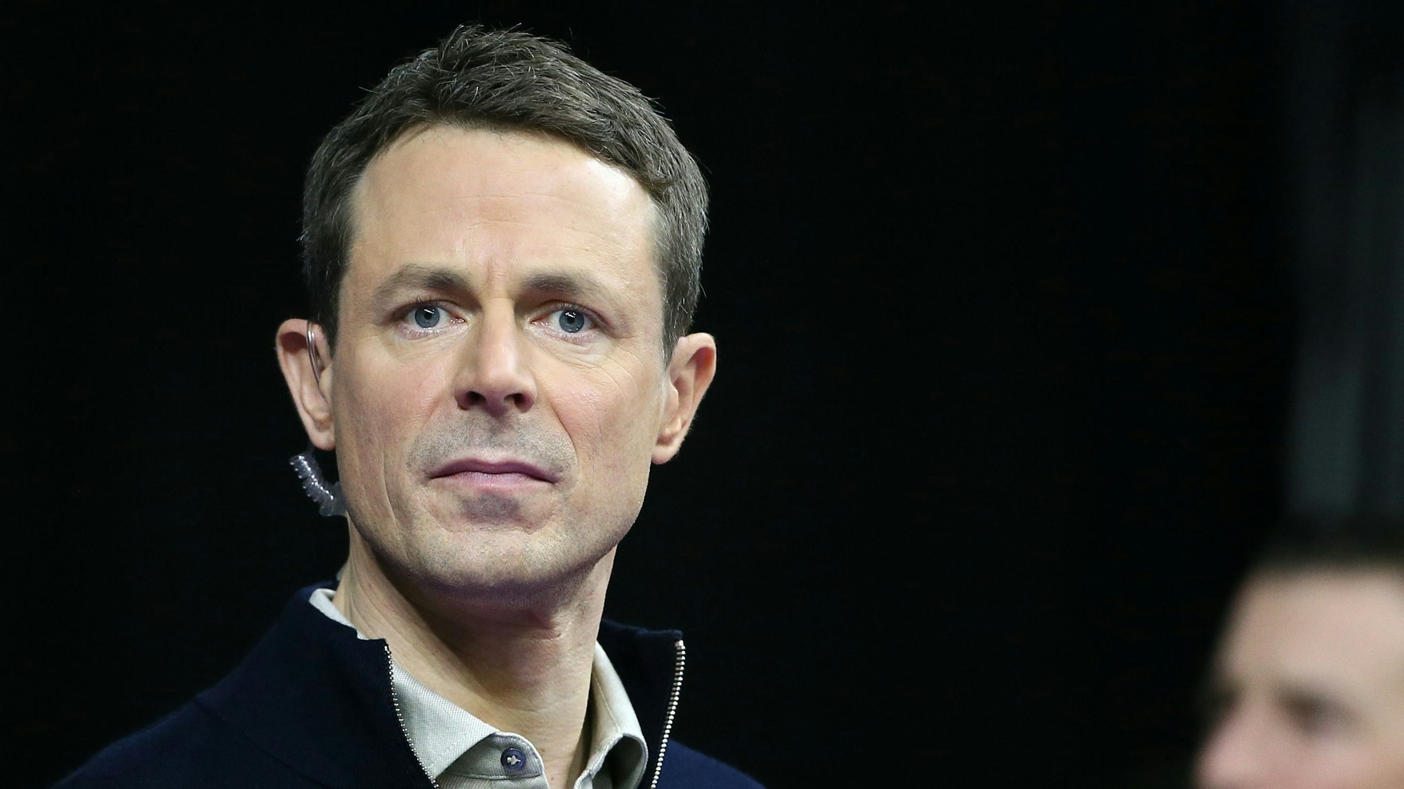 ARD-Moderator Alexander Bommes blickt bei einem Handball-Spiel ernst in die Kamera.