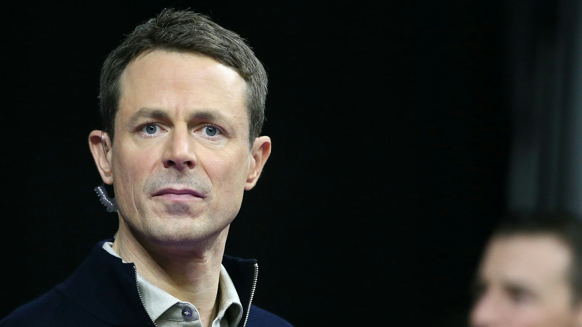 Moderator Alexander Bommes steht mit einem Mikrofon in Hemd und Pullover bei einer Live-Übertragung der ARD vor der Kamera.