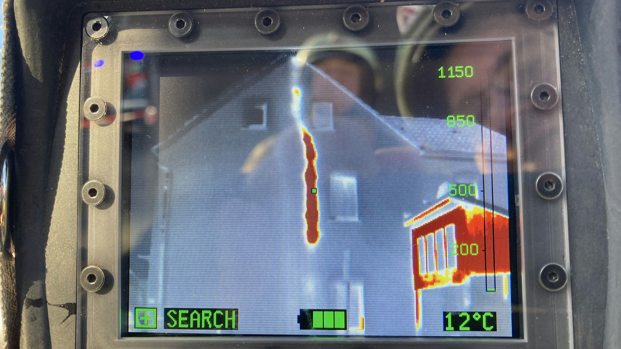 Auf einem Bildschirm ist eine Hausfassade und darin ein roter Streifen zu sehen,