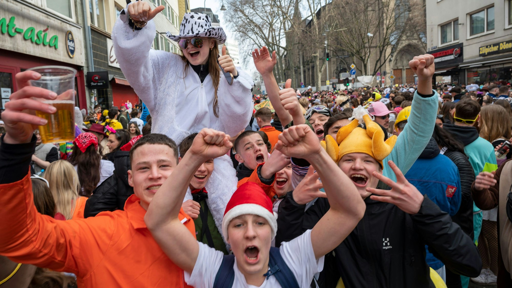 Junge Feiernde auf der Straße lachen in die Kamera.
