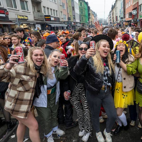 Eine Gruppe kostümierter Menschen feiert Karneval auf der Zülpicher Straße und lacht in die Kamera