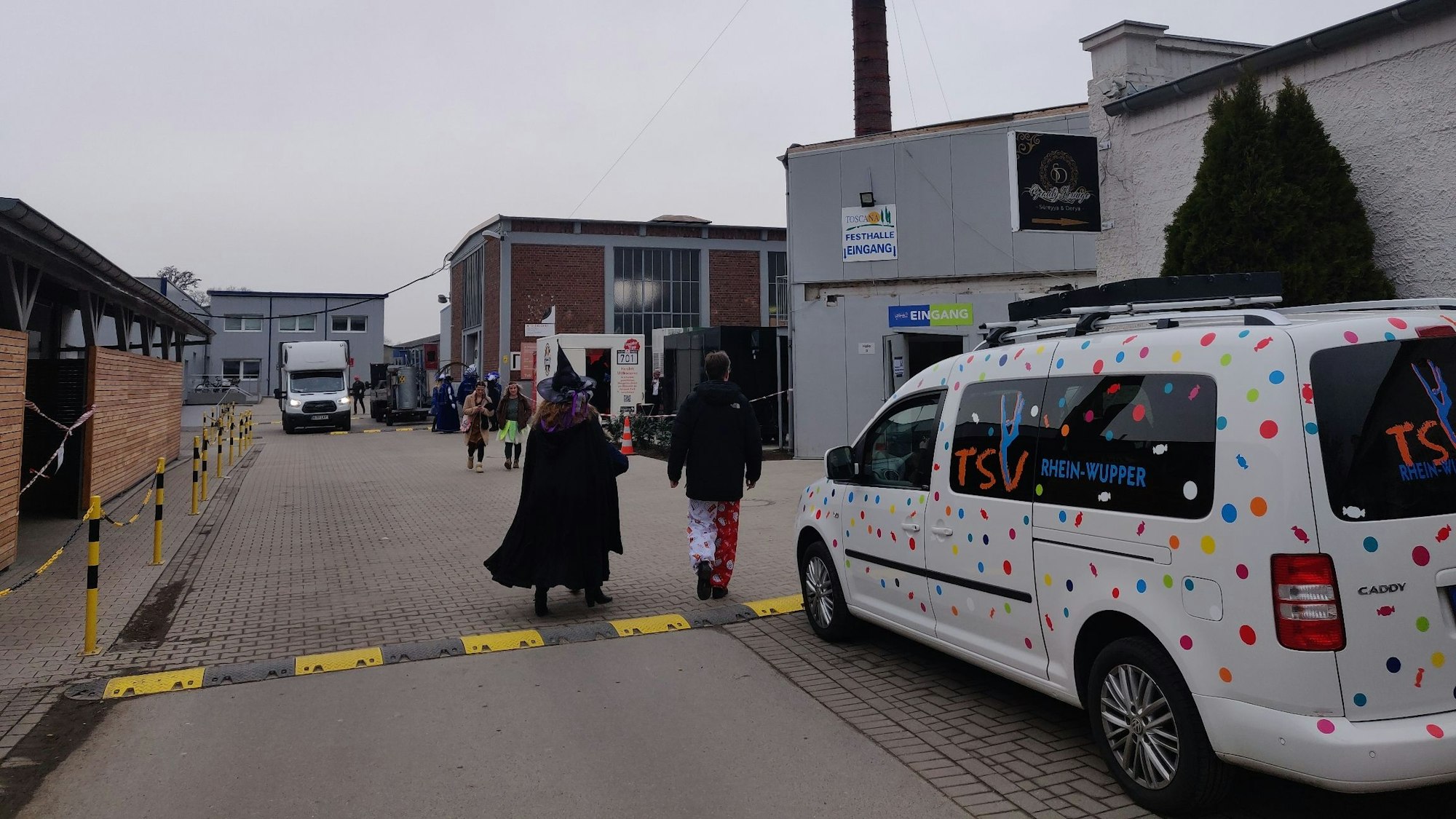 Außengelände vor der Toscana-Halle mit Lkw-Verkehr und kostümierten Fußgängern