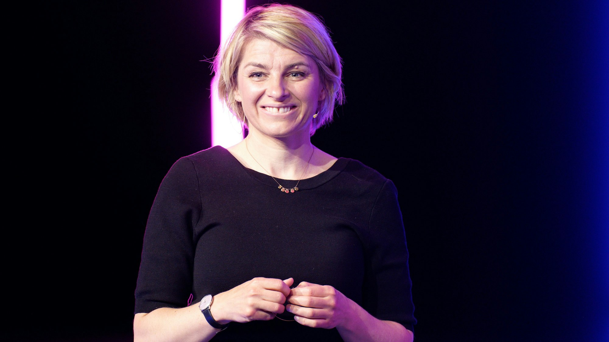 Die Moderatorin Sabine Heinrich steht bei einer Probe zur Veranstaltung "Remix2!“, sie lächelt in die Kamera.