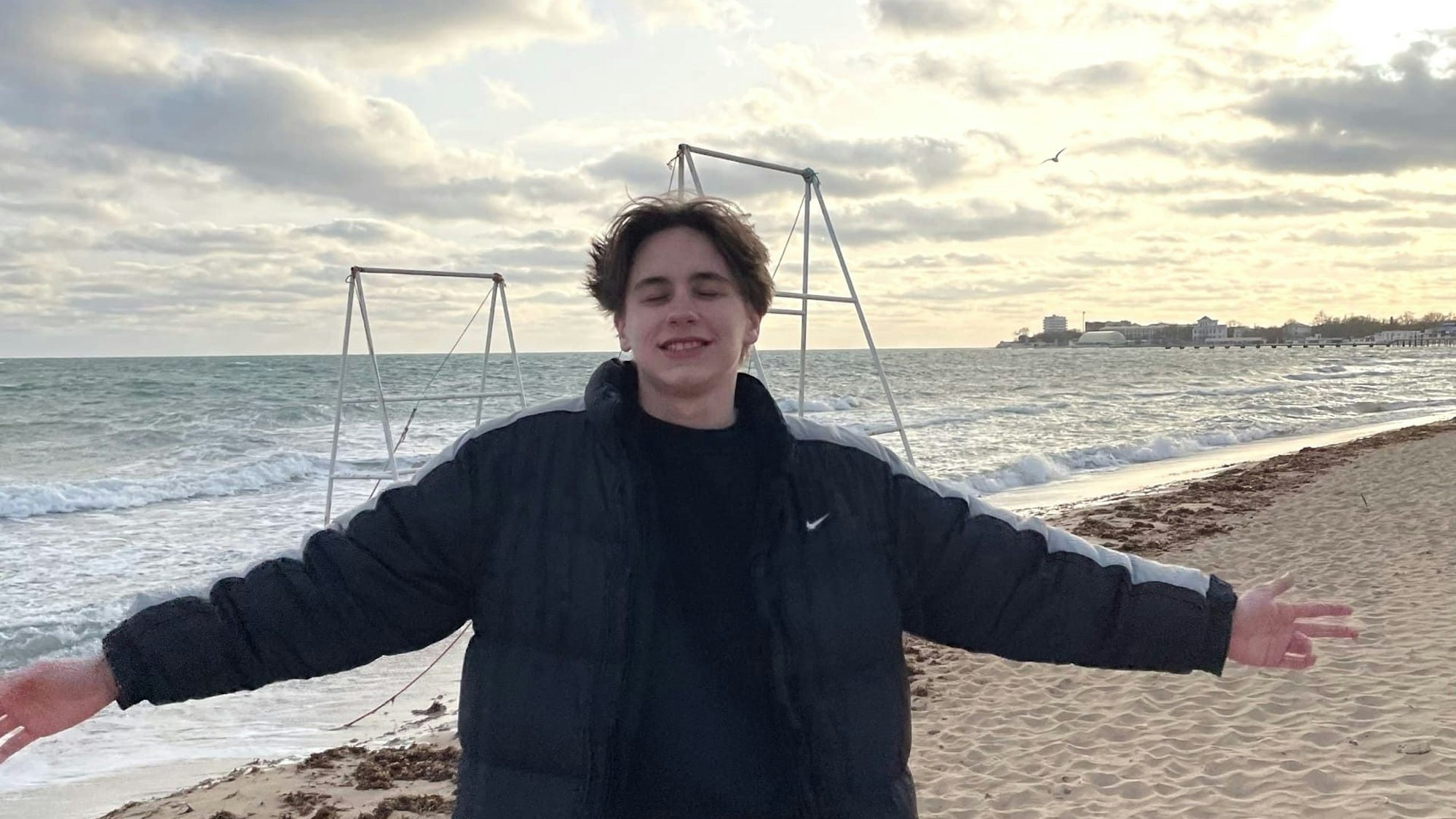 Tristan steht am Strand der Halbinsel Krim und breitet die Arme aus.