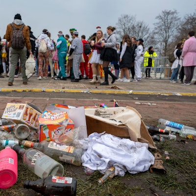 Das Foto zeigt leere Glasflaschen und Müll auf einer Wiese.