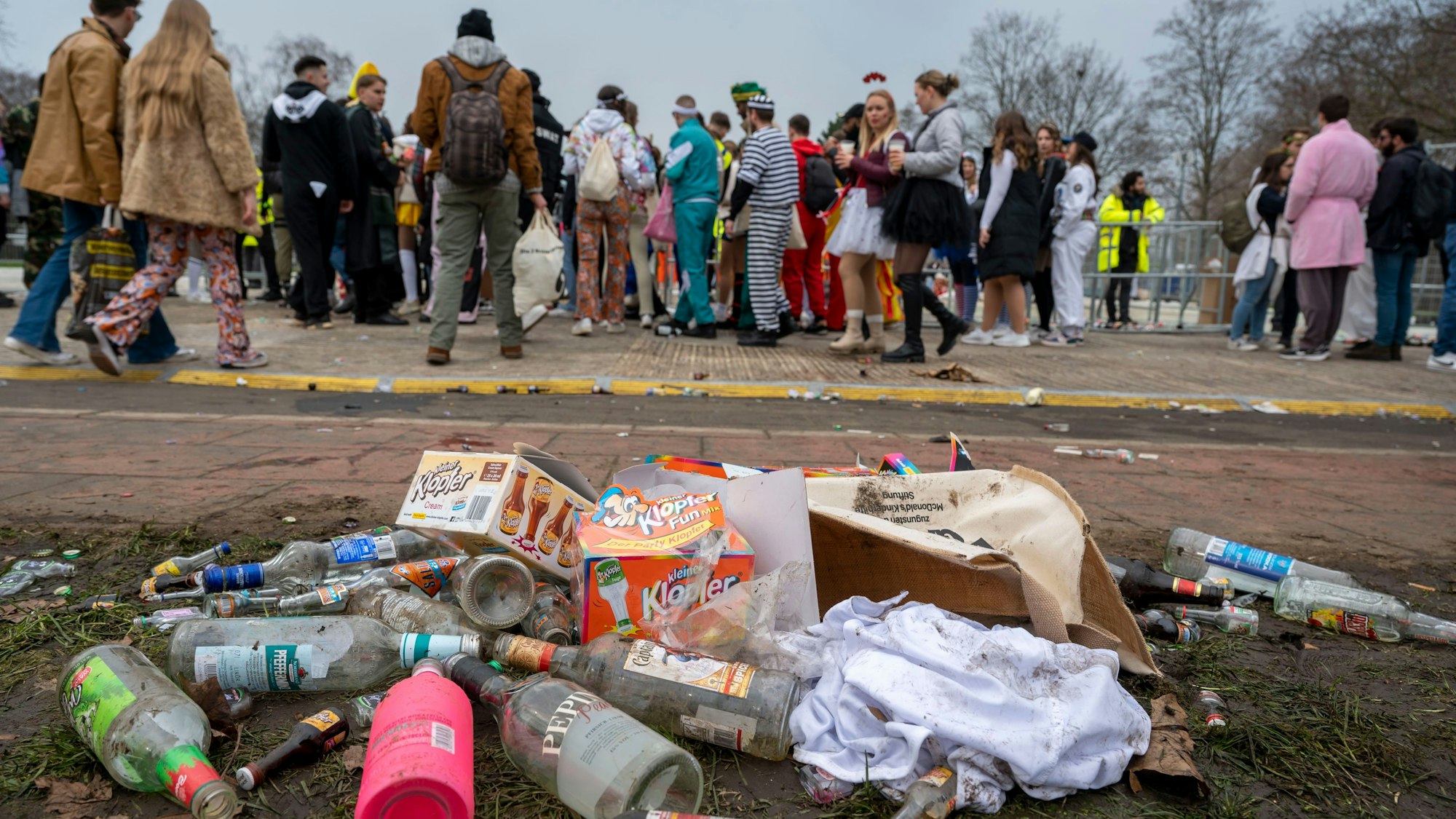 Das Foto zeigt leere Glasflaschen und Müll auf einer Wiese.