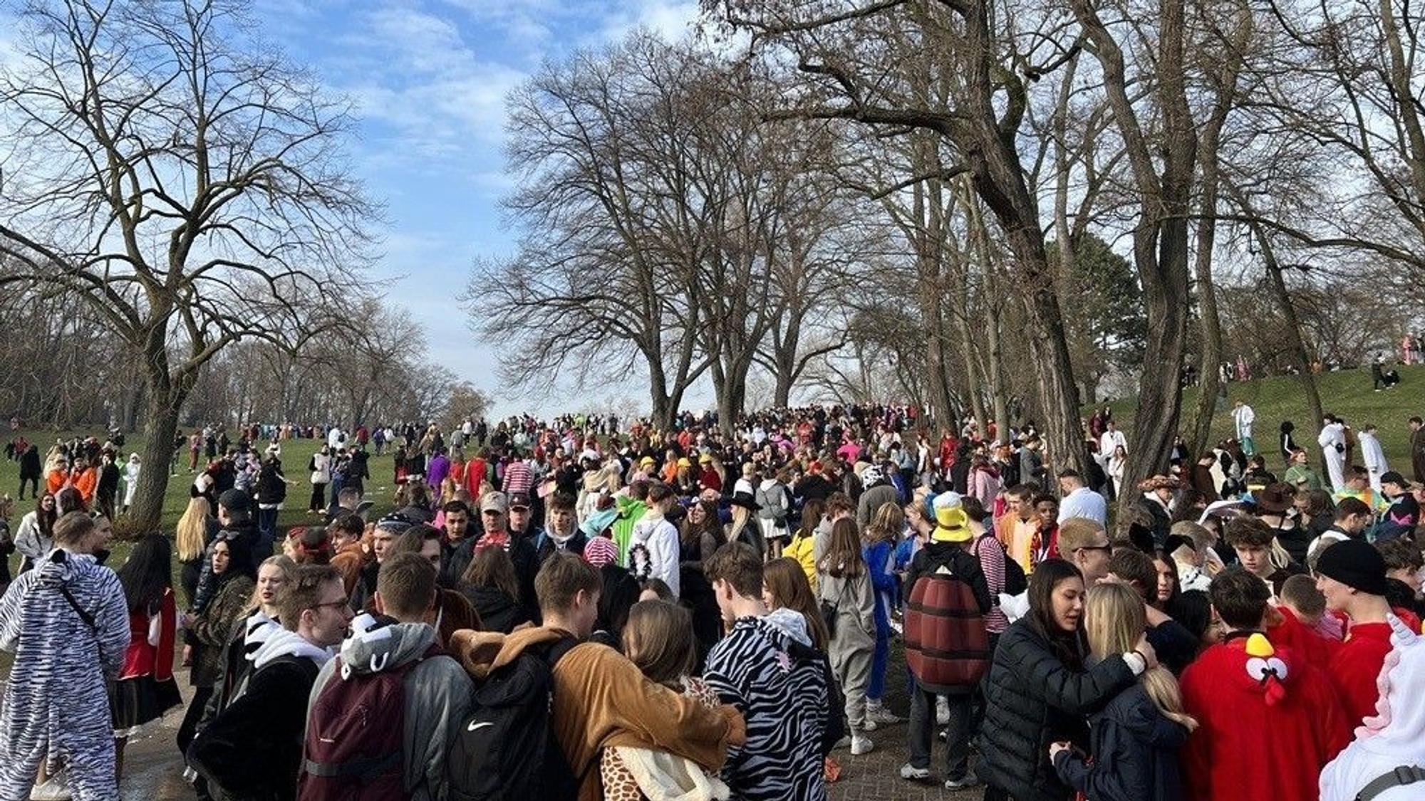 Junge, kostümierte Feiernde strömen über den Hügel im Hiroshima-Nagasaki-Park in Richtung Aachener Weiher.