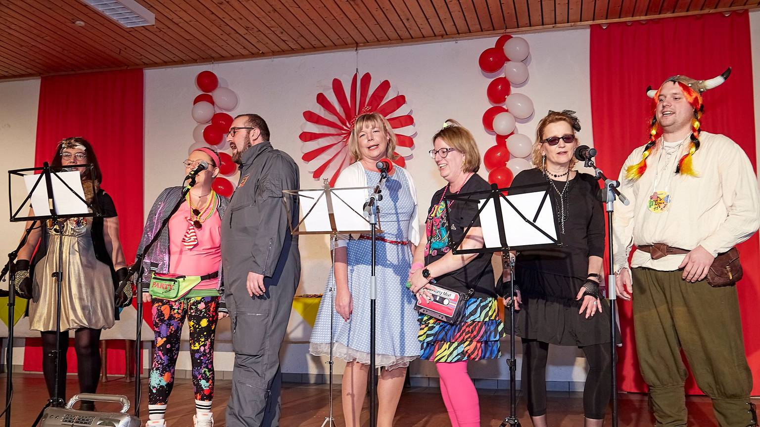 Karnevalisten stehen auf der Bühne und singen.