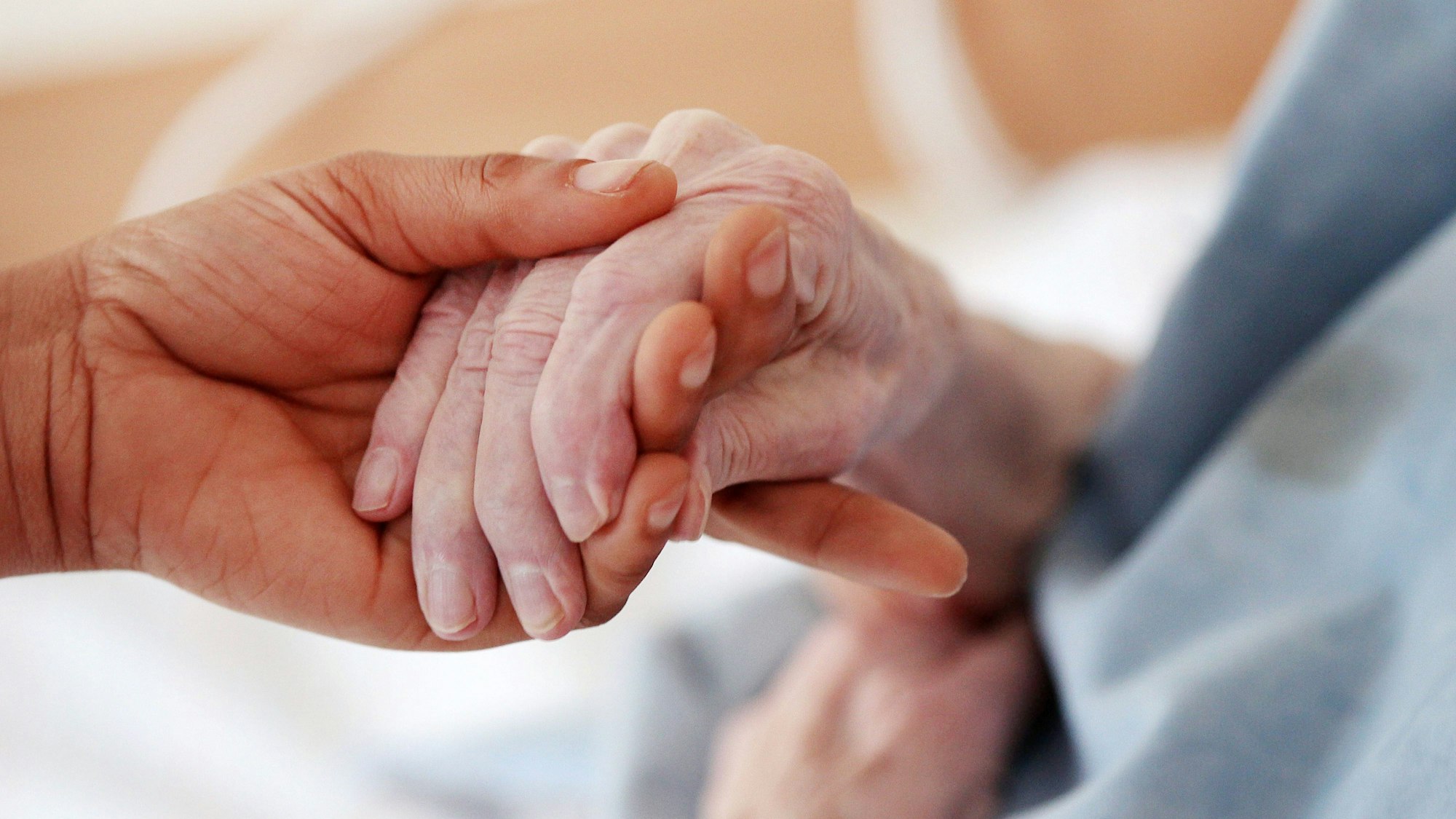 Eine Hand hält die Hand von einer älteren Person.