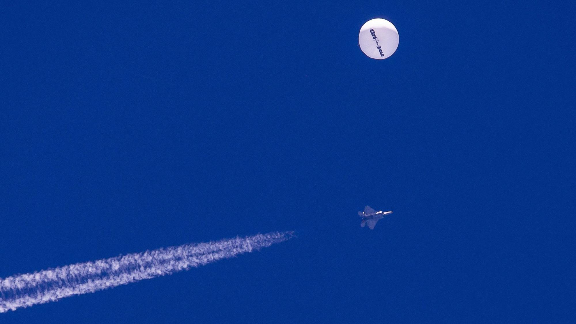 Ein F22-Kampfjet des US-Militärs fliegt in der Nähe des mutmaßlichen chinesischen Spionageballons. Beide sind deutlich am blauen Himmel zu sehen.